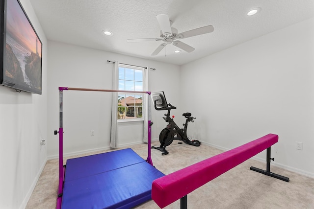 workout room featuring ceiling fan, light colored carpet, and a textured ceiling