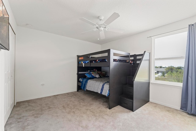 carpeted bedroom featuring ceiling fan and a textured ceiling