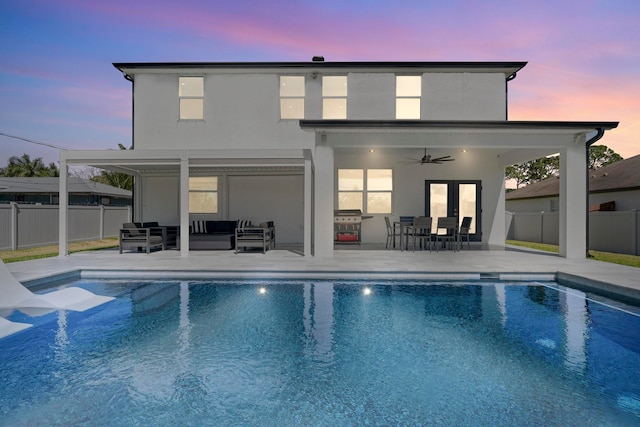 back house at dusk featuring a fenced in pool, an outdoor hangout area, ceiling fan, and a patio area