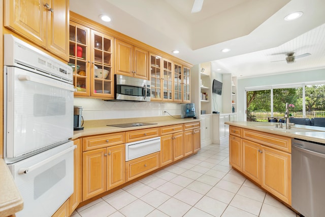 kitchen featuring ornamental molding, ceiling fan, sink, dishwasher, and light tile floors