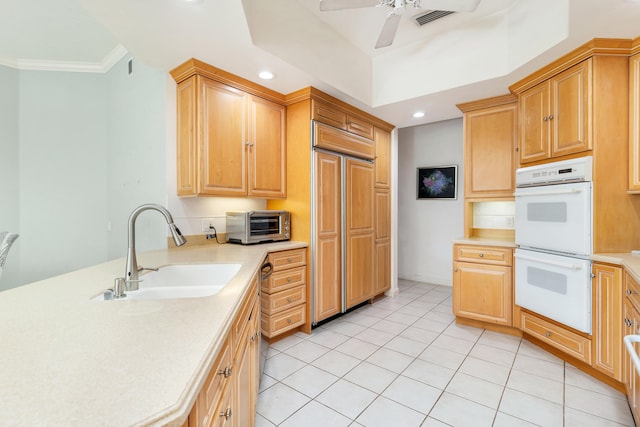 kitchen featuring double oven, kitchen peninsula, ceiling fan, crown molding, and light tile floors