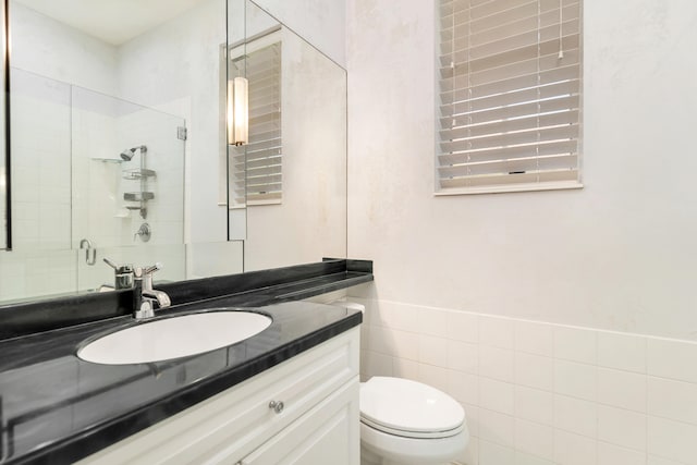 bathroom with tile walls, toilet, and vanity with extensive cabinet space