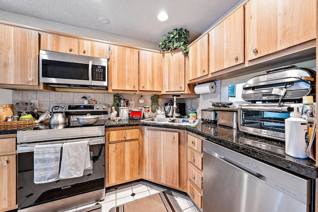 kitchen with appliances with stainless steel finishes, a textured ceiling, tasteful backsplash, and light tile floors