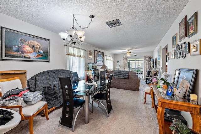 dining space with light colored carpet, a textured ceiling, and ceiling fan with notable chandelier