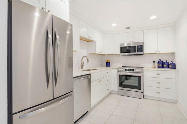 kitchen featuring appliances with stainless steel finishes, decorative backsplash, sink, white cabinets, and light tile patterned floors