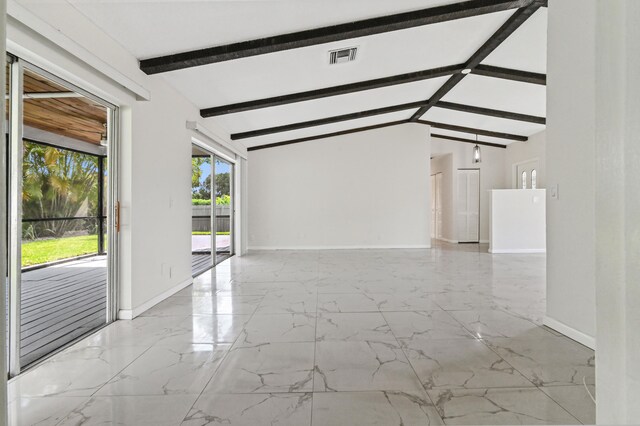 tiled empty room with beamed ceiling and high vaulted ceiling