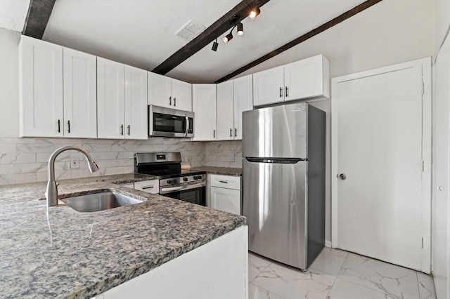 kitchen with backsplash, vaulted ceiling, stainless steel appliances, white cabinets, and sink