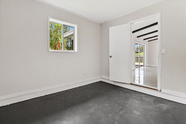 unfurnished room with vaulted ceiling with beams, concrete flooring, and a wealth of natural light