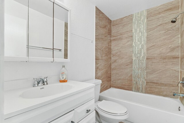 full bathroom featuring oversized vanity, tiled shower / bath combo, and toilet