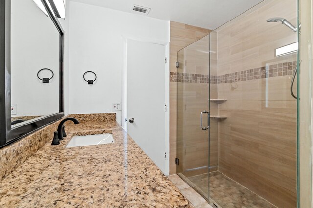 bathroom featuring a shower with shower door and vanity