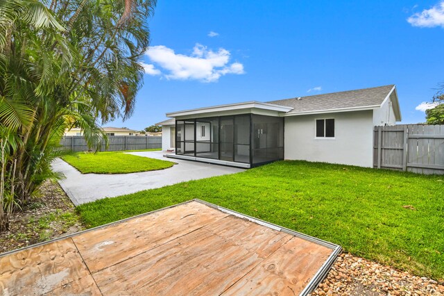 back of property featuring a patio, a yard, and a sunroom