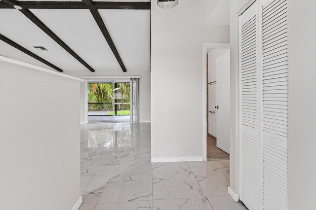 hallway featuring lofted ceiling with beams and light tile floors