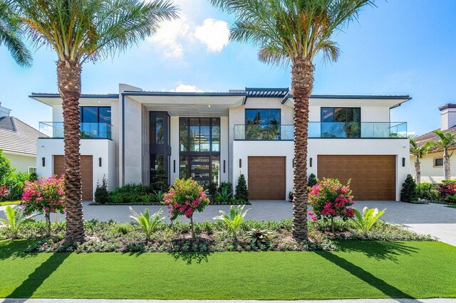 contemporary house featuring a garage, a balcony, and a front lawn