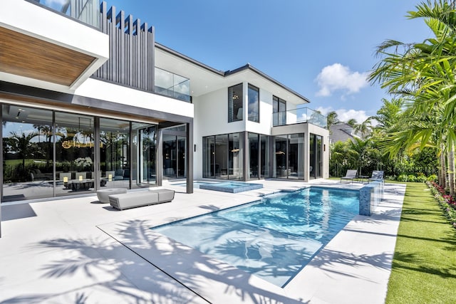 rear view of property with a balcony, a pool with hot tub, and a patio