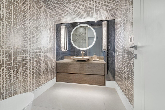 bathroom featuring vanity, tile patterned floors, vaulted ceiling, toilet, and tile walls