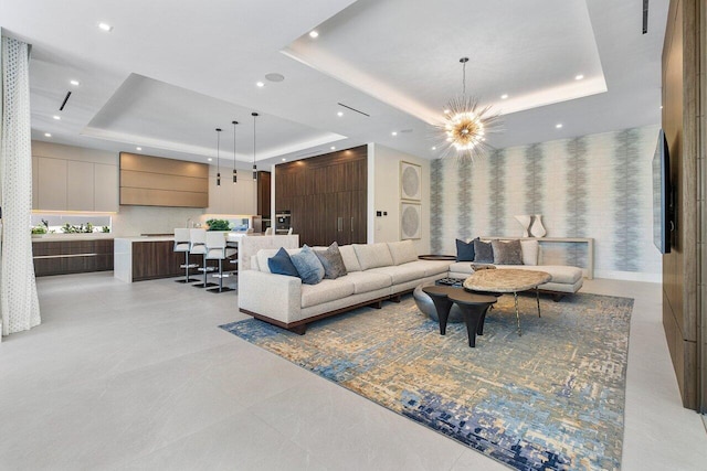 living room with an inviting chandelier and a raised ceiling