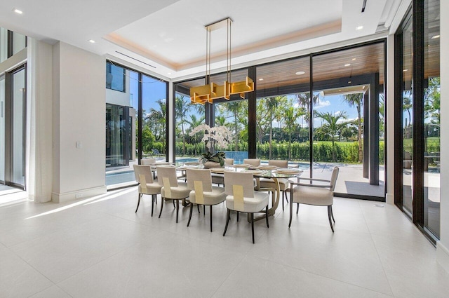 dining space with light tile patterned floors, a raised ceiling, and plenty of natural light