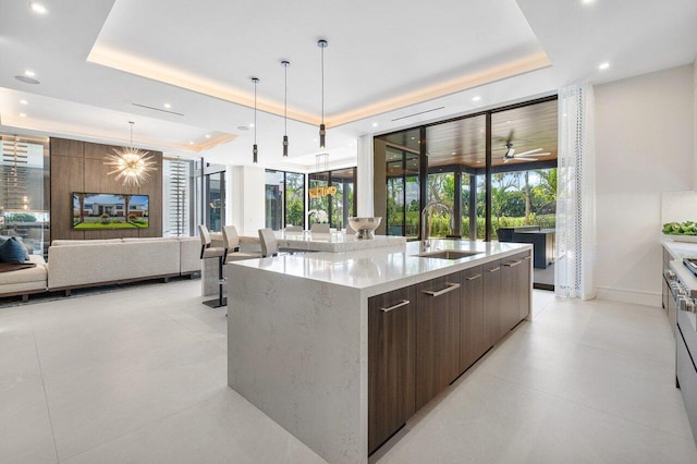 kitchen with a tray ceiling, pendant lighting, sink, and a spacious island