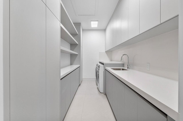 clothes washing area with washer and dryer, cabinets, light tile patterned floors, and sink