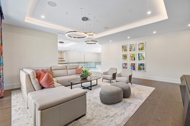 living room with a chandelier, wood-type flooring, and a tray ceiling