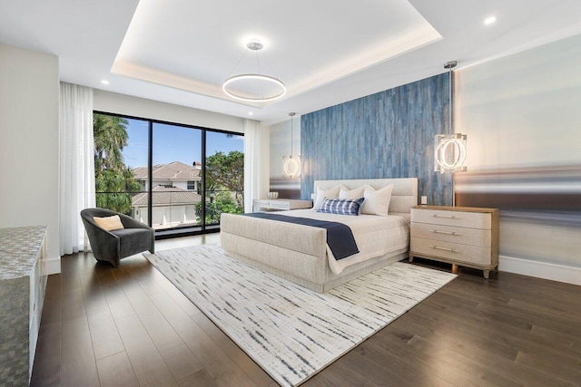 bedroom with a tray ceiling and dark hardwood / wood-style floors