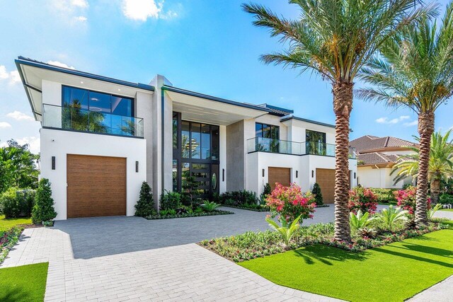 contemporary house featuring a balcony, a front yard, and a garage