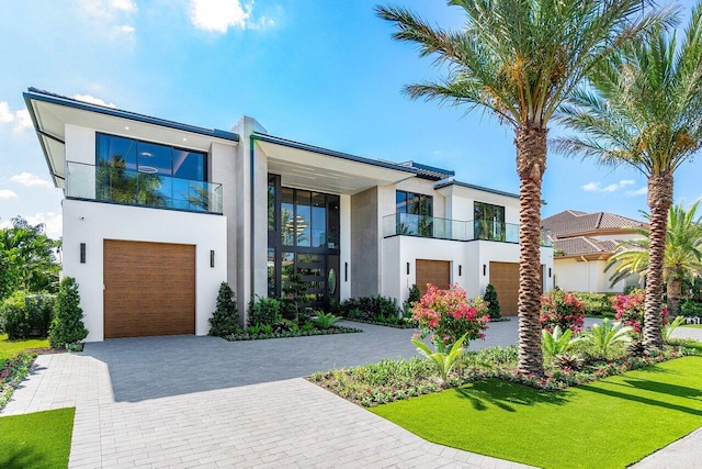 contemporary home with a balcony, a garage, and a front yard