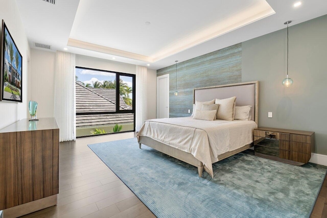 bedroom with wood-type flooring and a tray ceiling