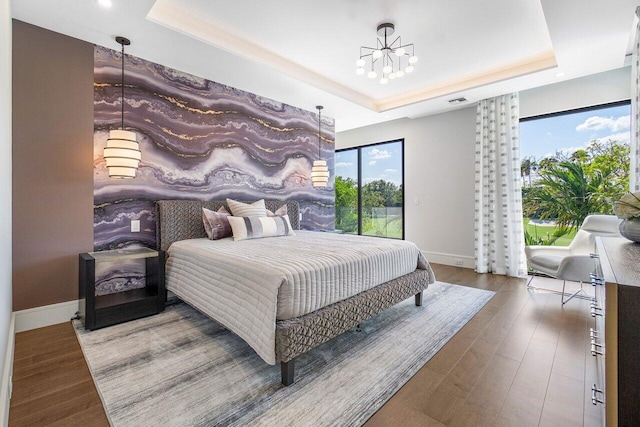 bedroom featuring a raised ceiling, a chandelier, and wood-type flooring