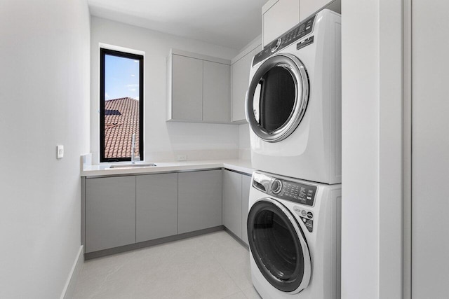 clothes washing area featuring stacked washer / dryer, sink, and cabinets