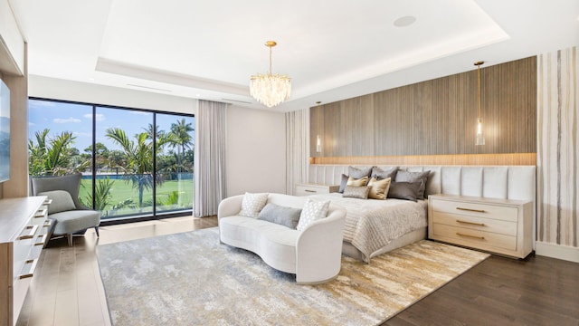 bedroom featuring dark wood-type flooring, access to outside, a raised ceiling, multiple windows, and a chandelier