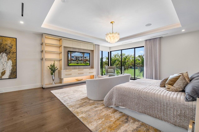 bedroom with a chandelier, dark hardwood / wood-style flooring, and a raised ceiling