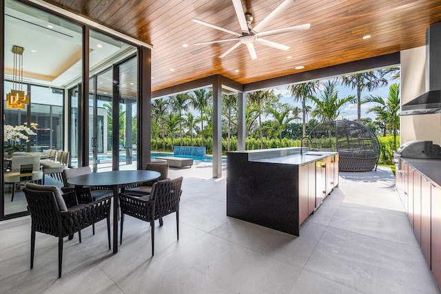 view of patio with an outdoor kitchen, a swimming pool, ceiling fan, sink, and a grill