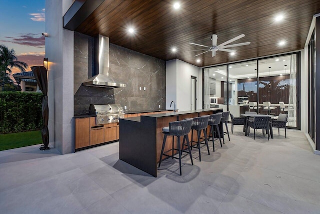 bar with ceiling fan, wooden ceiling, sink, and wall chimney range hood