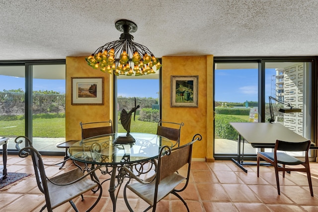 tiled dining space with a chandelier, a wall of windows, and a textured ceiling