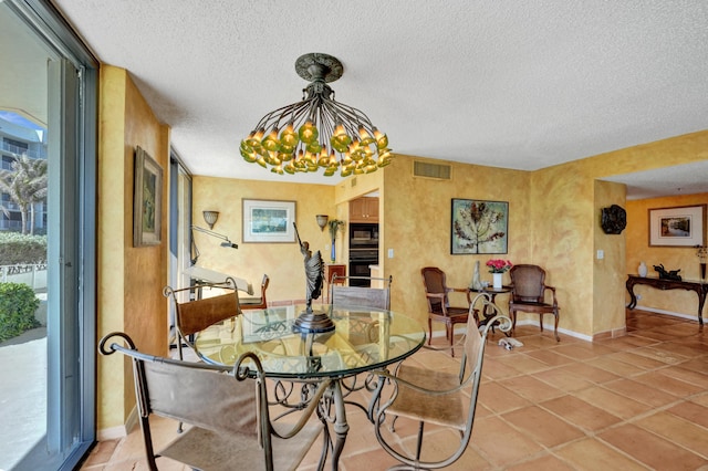 tiled dining room with a chandelier and a textured ceiling