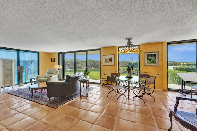 living room featuring a textured ceiling, a wall of windows, light tile floors, and a notable chandelier