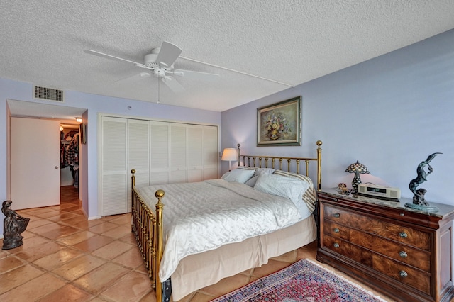 bedroom featuring a closet, a textured ceiling, ceiling fan, and light tile floors