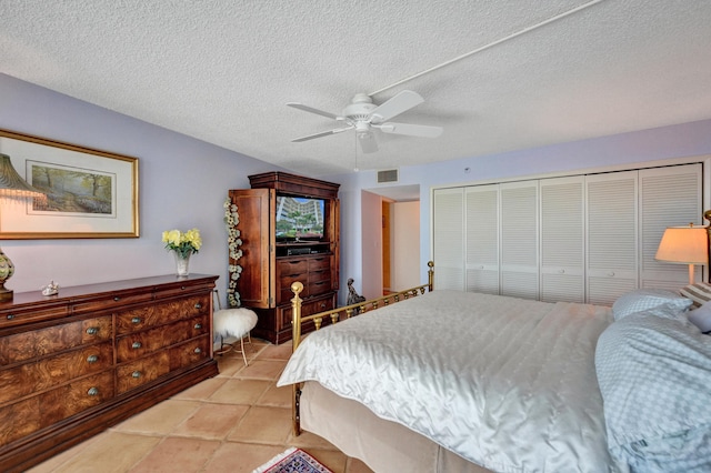 bedroom with ceiling fan, light tile floors, and a textured ceiling