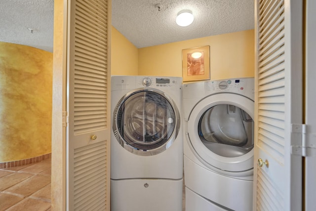 laundry area with a textured ceiling, washing machine and dryer, and tile floors