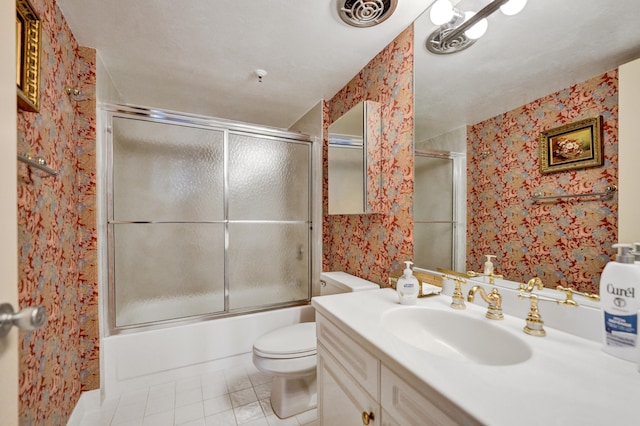 full bathroom with vanity with extensive cabinet space, toilet, bath / shower combo with glass door, and tile flooring