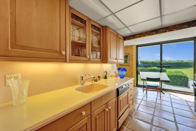 kitchen with sink, a paneled ceiling, light tile floors, and dishwashing machine