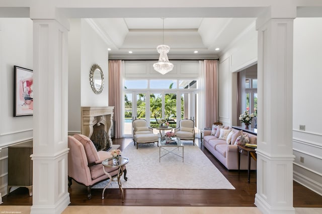 living room with a raised ceiling, decorative columns, hardwood / wood-style flooring, and a wealth of natural light