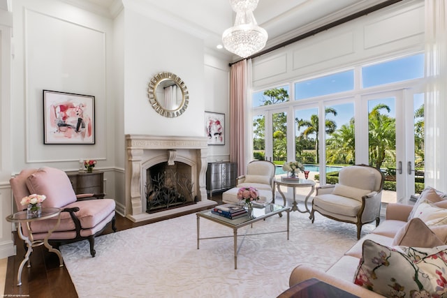 living room featuring hardwood / wood-style flooring, ornamental molding, french doors, and a notable chandelier