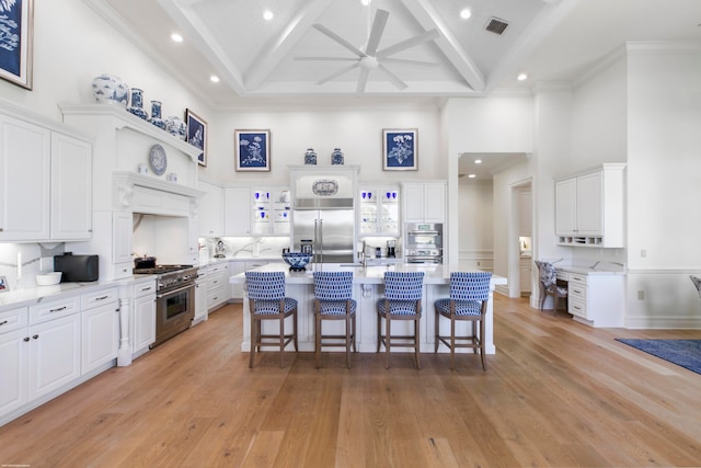 kitchen with light hardwood / wood-style flooring, an island with sink, white cabinetry, and high end appliances