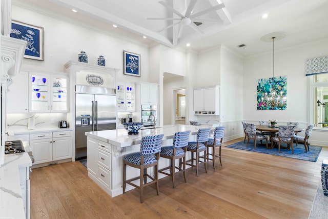 kitchen with a center island, light hardwood / wood-style floors, white cabinets, and built in fridge