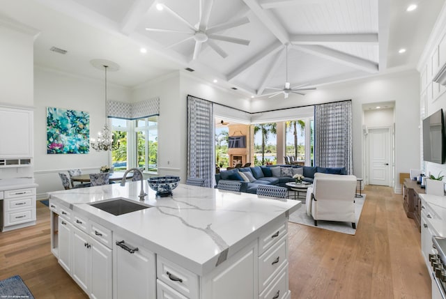 kitchen with a kitchen island, white cabinets, sink, light hardwood / wood-style flooring, and pendant lighting