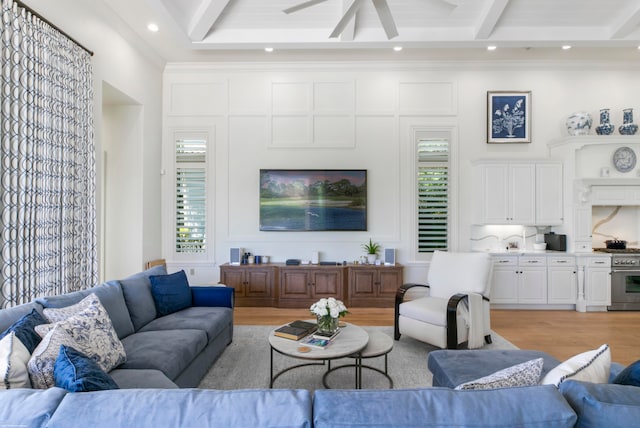 living room featuring beamed ceiling, ceiling fan, and light hardwood / wood-style flooring