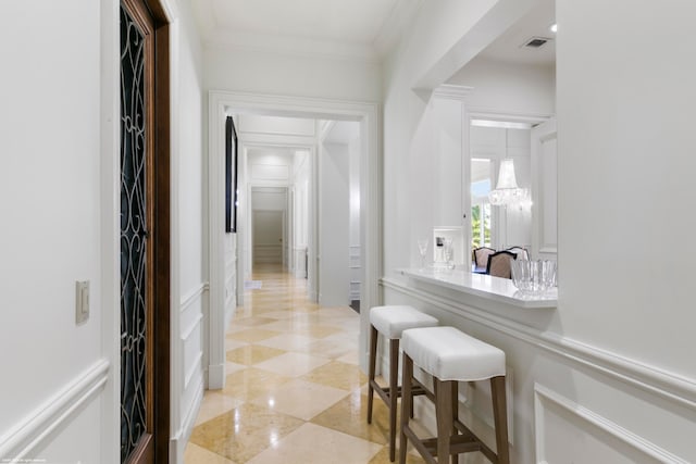 corridor with ornamental molding, a chandelier, and light tile flooring