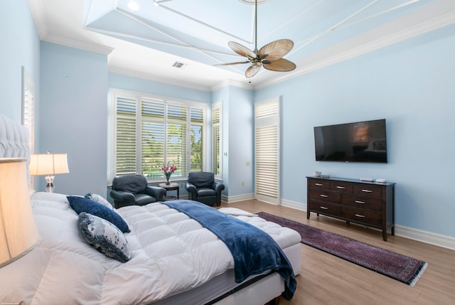 bedroom featuring hardwood / wood-style floors, ceiling fan, a raised ceiling, and ornamental molding